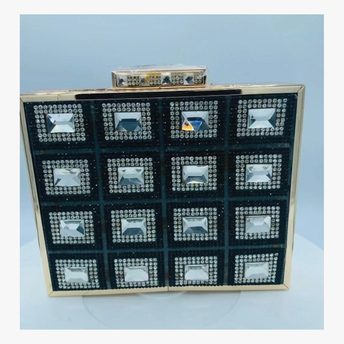 Front view of the Diamond Clutch showing black panels, clear embellishments, and gold-tone frame