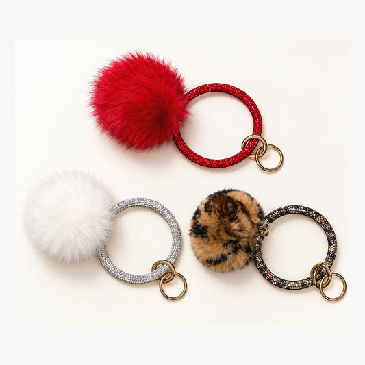 Red, white, and leopard print pom keychains with sparkling circular handles