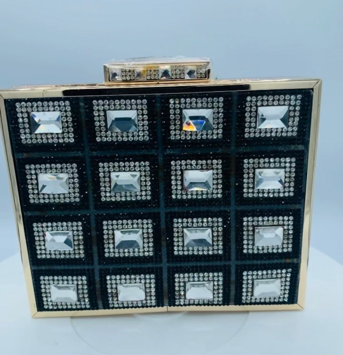 Front view of the Diamond Clutch showing black panels, clear embellishments, and gold-tone frame